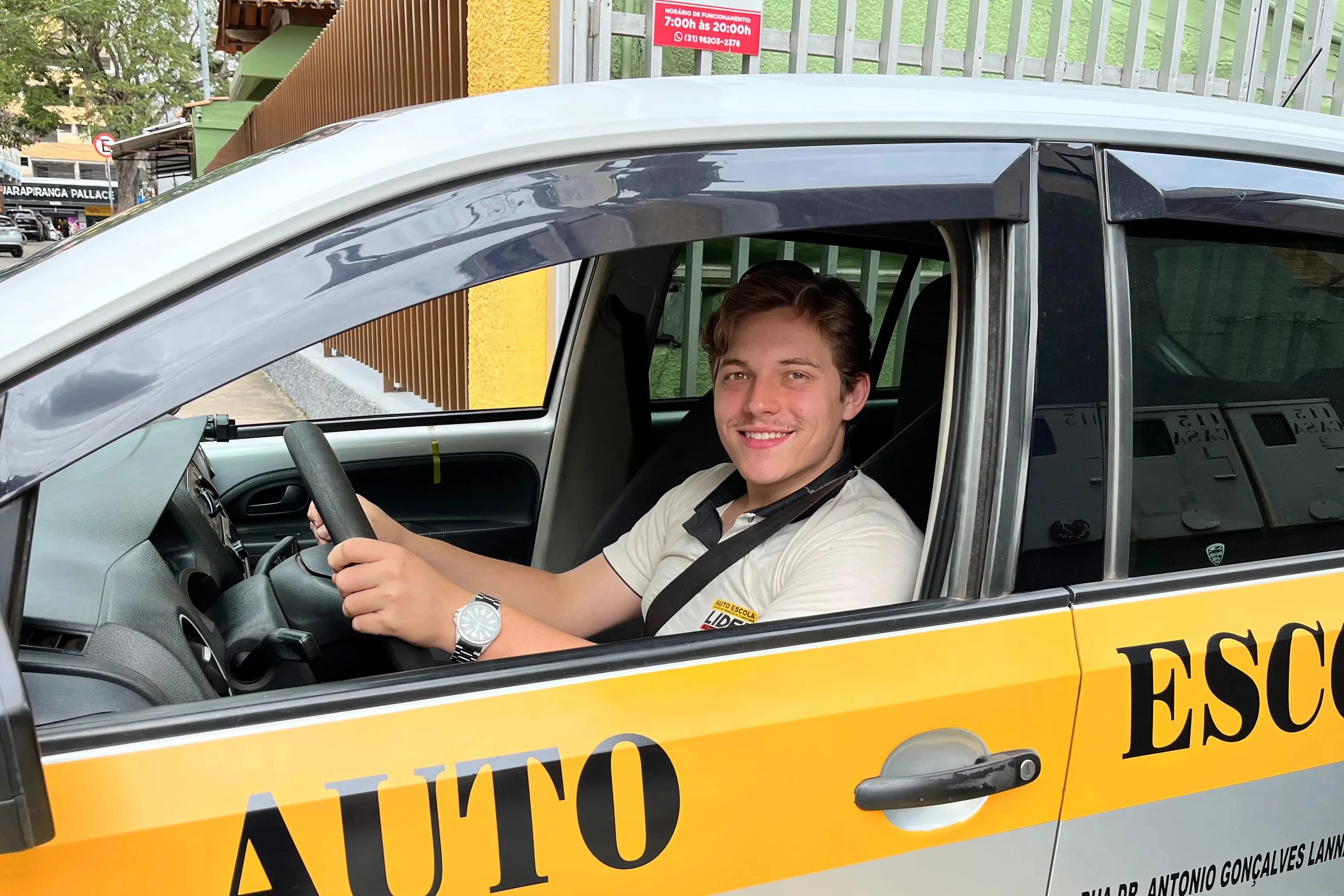 Instrutor sorrindo com as mãos no volante.